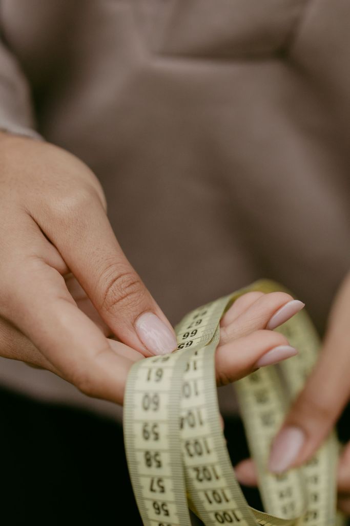 Hands holding a yellow measuring tape, close-up, for tracking progress