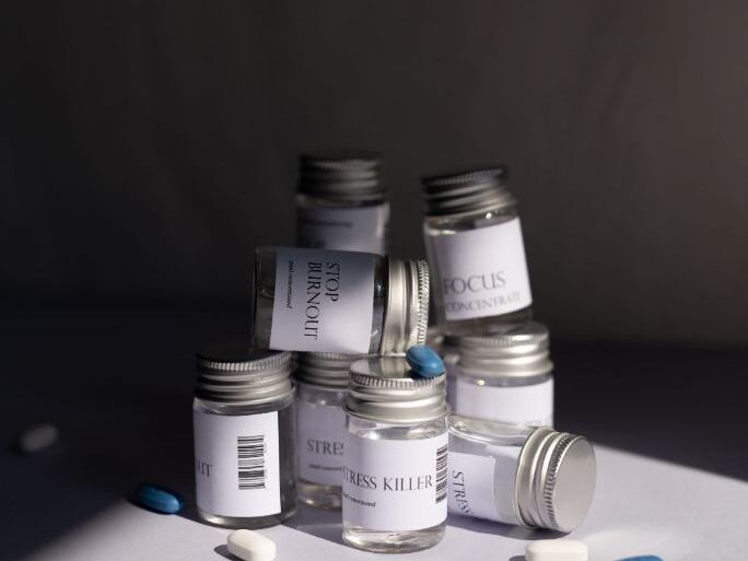 Labeled prescription bottles with loose blue and white capsules on a grey surface